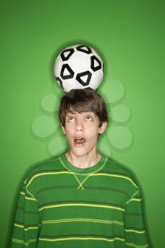 Royalty Free Photo of a Teenage Boy Balancing a Soccer Ball on His Head