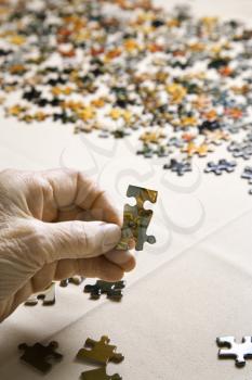 Royalty Free Photo of an Elderly Woman's Hand Holding a Puzzle Piece