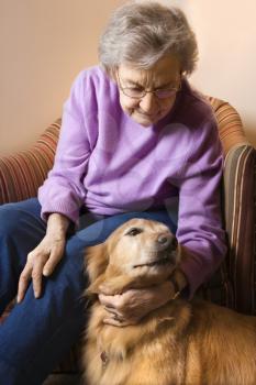 Royalty Free Photo of an Elderly Woman in a Bedroom at Retirement Community Center Petting the Therapy Dog