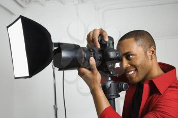 Royalty Free Photo of an African American Young Male Looking Through Camera on a Tripod