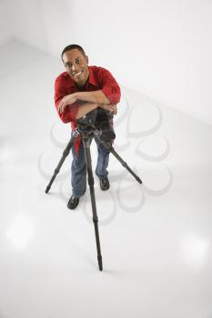 Royalty Free Photo of a Male Photographer Leaning on a Tripod and Smiling