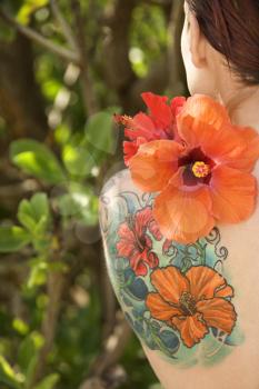 Royalty Free Photo of Back view of tattooed Caucasian woman with Hibiscus flower over her shoulder in Maui, Hawaii, USA