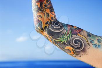 Royalty Free Photo of a Close-up of a Tattooed Woman's Arm With Pacific Ocean in Background in Maui, Hawaii, USA