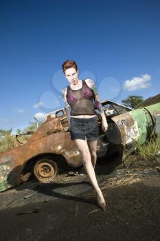 Royalty Free Photo of a Sexy tattooed Caucasian woman walking towards viewer seductively in junkyard