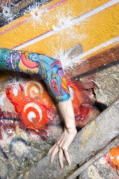 Royalty Free Photo of a Tattooed Woman's Arm Against a Graffiti Covered Wall
