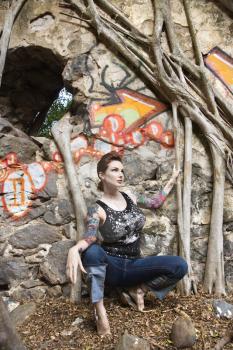 Royalty Free Photo of a Tattooed Woman Next to a Wall Covered in Graffiti 