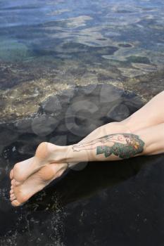 Royalty Free Photo of Legs of a Tattooed Woman Lying in a Tidal Pool in Maui, Hawaii, USA