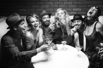 Royalty Free Photo of a Group of Males and Females Sitting at a Table in the Lounge Laughing