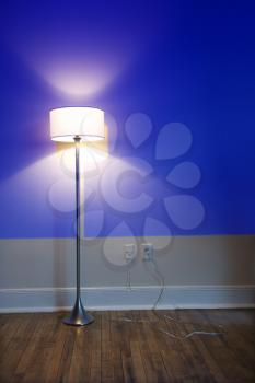 Royalty Free Photo of a Blue Projection Light on a Wall With a Bright Floor Lamp