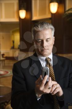 Royalty Free Photo of a Businessman Dialing a Cellphone in a Hotel Lobby