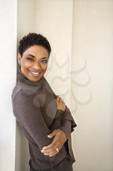 Royalty Free Photo of a Woman Standing Leaning Against a Wall Smiling