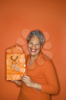 Royalty Free Photo of an Older Female Holding a Gift Bag Smiling