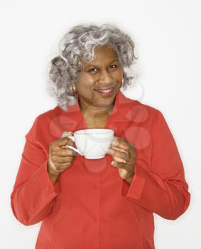 Royalty Free Photo of an Older Woman Smiling and Holding a Cup of Coffee