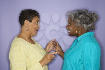 Mature adult African American female pointing at eachother.