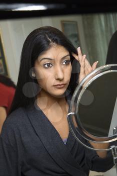 Close up of Asian/Indian young woman looking in mirror primping.