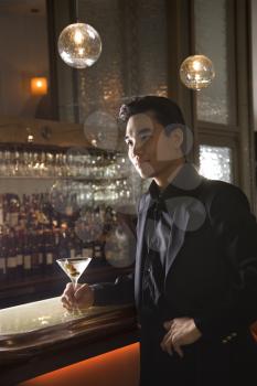Royalty Free Photo of a Man Standing at a Bar Holding a Cocktail