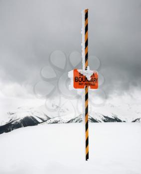 Royalty Free Photo of a Ski Area Trail Boundary Sign in a Snow-Covered Mountain Scene