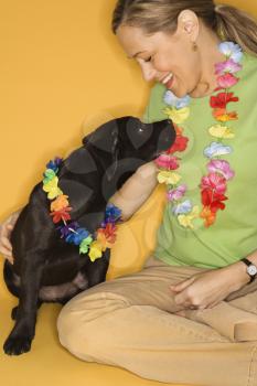 Royalty Free Photo of a Female Sitting With a Black Puppy Wearing Leis