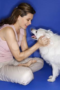 Royalty Free Photo of a Woman Petting a Fluffy White Dog