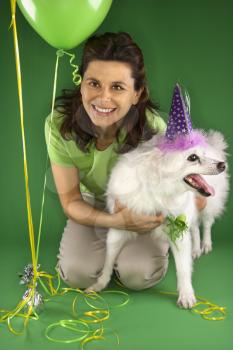 Royalty Free Photo of a Woman Kneeling With a Dog Wearing a Party Hat
