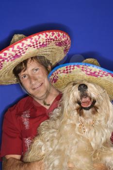 Royalty Free Photo of a Fluffy Brown Dog and a Man Wearing Mexican Sombreros