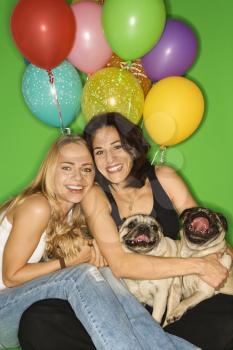 Royalty Free Photo of Women Sitting With Their Dogs and Balloons