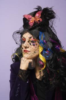 Portrait of Caucasian woman in unique makeup and clothing against purple background.