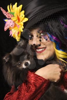 Royalty Free Photo of a Woman in Unique Makeup Holding a Black Pomeranian Dog