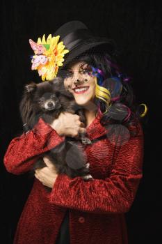 Royalty Free Photo of a Woman in Unique Makeup Holding a Black Pomeranian Dog