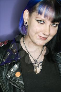 Royalty Free Photo of a Woman With Blue Hair, Tattoos, and a Spike Collar Against an Orange Background