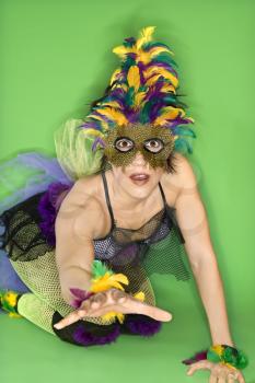 Royalty Free Photo of a Portrait of a Woman in a Mardi Gras Costume and Mask Kneeling on the Floor With Hand Reaching