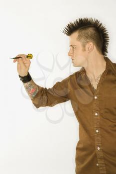 Royalty Free Photo of a Side View of a Man With a Mohawk Holding a Dart