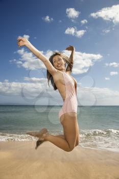 Royalty Free Photo of a Woman in a Swimsuit Jumping into the Air at a Beach in Maui Hawaii