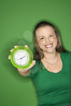 Royalty Free Photo of a Woman Holding Out an Alarm Clock Smiling