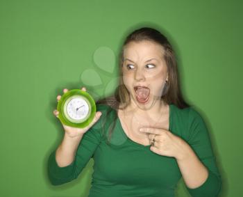 Royalty Free Photo of a Woman Holding and Pointing to a Clock