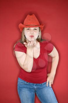 Royalty Free Photo of a Young Female Blowing a Kiss While Wearing a Red Cowboy Hat