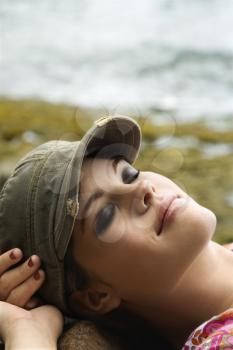 Royalty Free Photo of a Woman Wearing a Hat Lying Down with Hands Behind Her Head