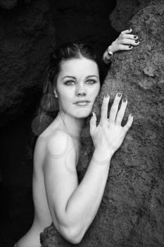 Royalty Free Photo of a Young Nude Woman Leaning Against a Rock and Looking at Viewer