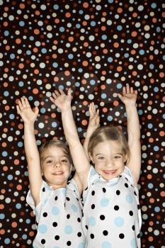 Female children Caucasian twins looking at viewer with arms raised.