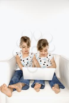Female children Caucasian twins playing with laptop computer.