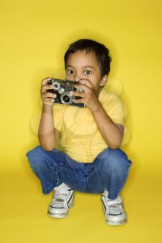 Royalty Free Photo of a Boy Kneeling Holding a Camera