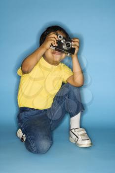 Royalty Free Photo of a  Boy Kneeling With a Camera