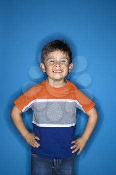 Male Hispanic boy standing with hands on hips.