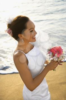 Royalty Free Photo of a Bride Holding a Bouquet on a Beach