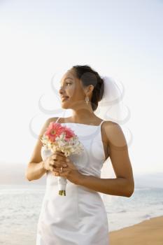 Royalty Free Photo of a Bride Holding a Bouquet on the Beach