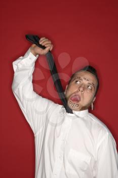 Royalty Free Photo of a Man  With Tattoos and Piercings Holding Up a Necktie 