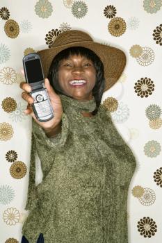 Royalty Free Photo of a Woman  in Front of a Vintage Pattern Background Holding Out a Cellphone