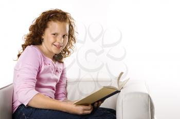 Caucasian female child sitting reading book.