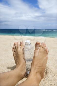 Royalty Free Photo of a Caucasian Woman's Feet and Water Bottle on the Beach