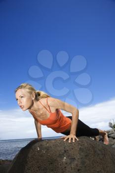 Royalty Free Photo of a Woman Doing a Push Up on a Rock